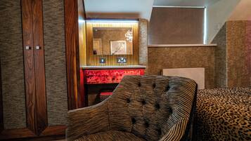 Una habitación con un sillón a rayas, un sofá estampado de leopardo y un espejo con marco rojo.