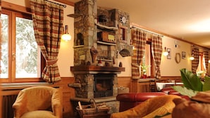 Una habitación acogedora con chimenea de piedra, muebles de madera y vistas a los árboles a través de la ventana.