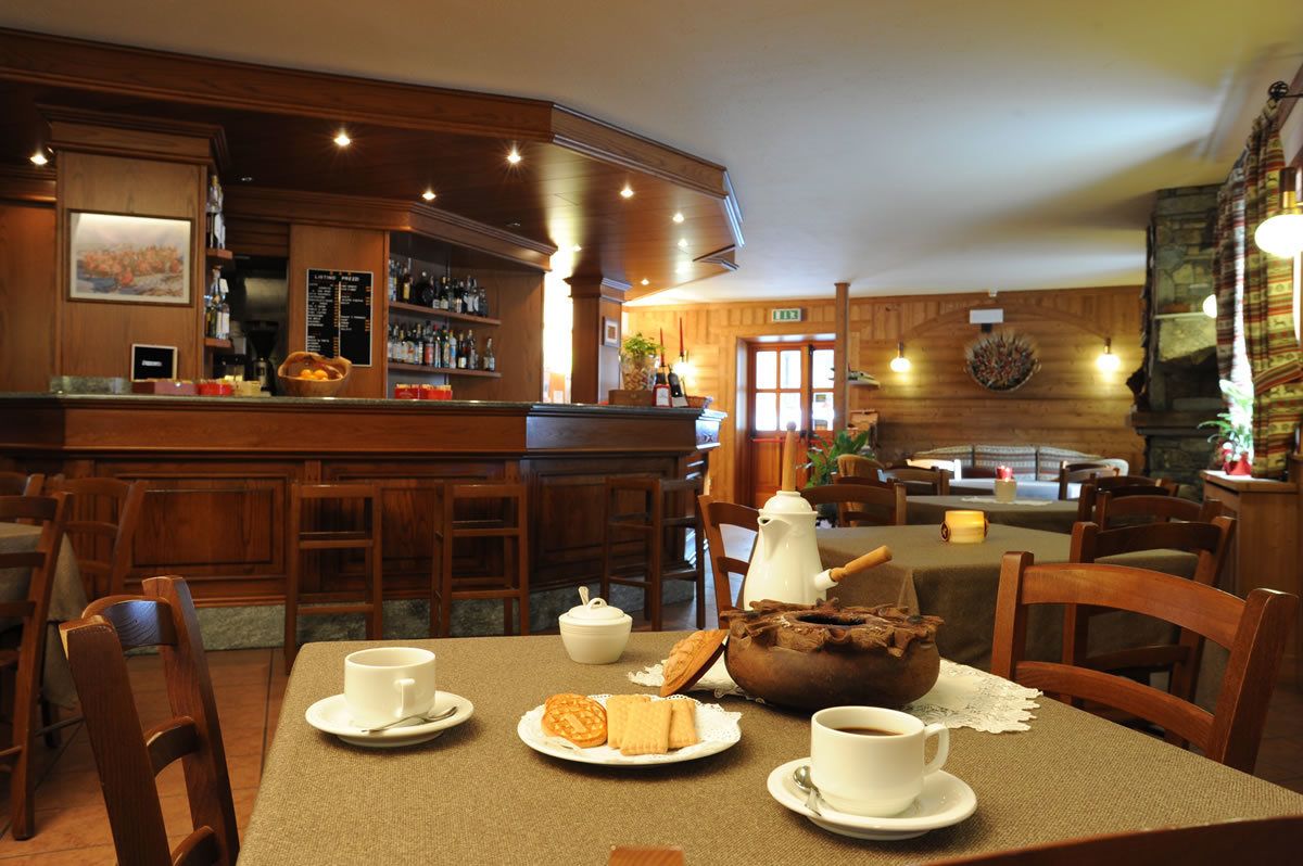 Un accogliente ristorante con arredamento in legno, un'area bar e tavoli apparecchiati per i pasti.