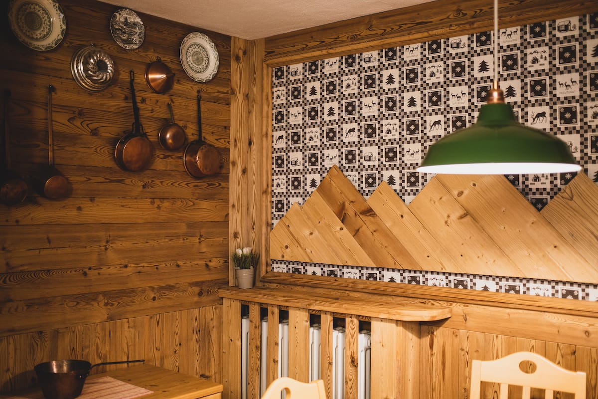 Une cuisine rustique aux murs en bois, avec un pare-feu à carreaux et des ustensiles de cuisine en cuivre accrochés au mur.