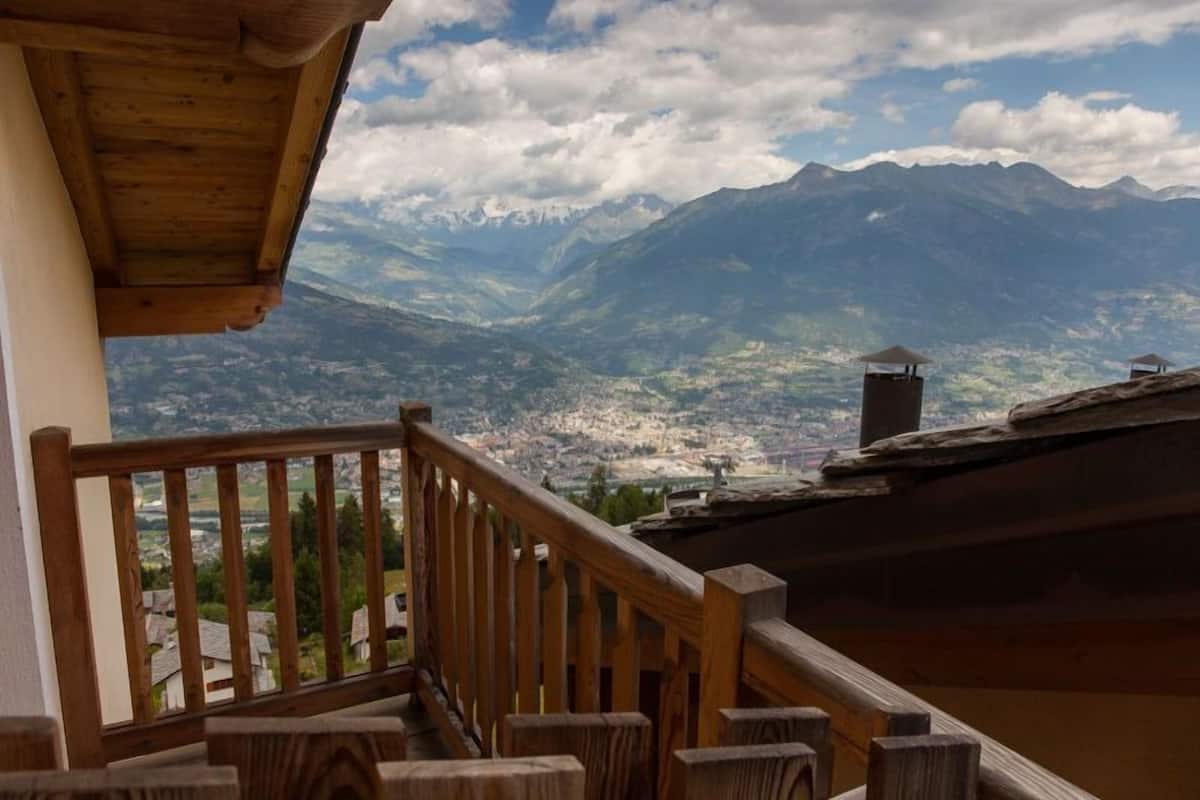 Un balcon en bois offrant une vue sur une vallée et des montagnes.