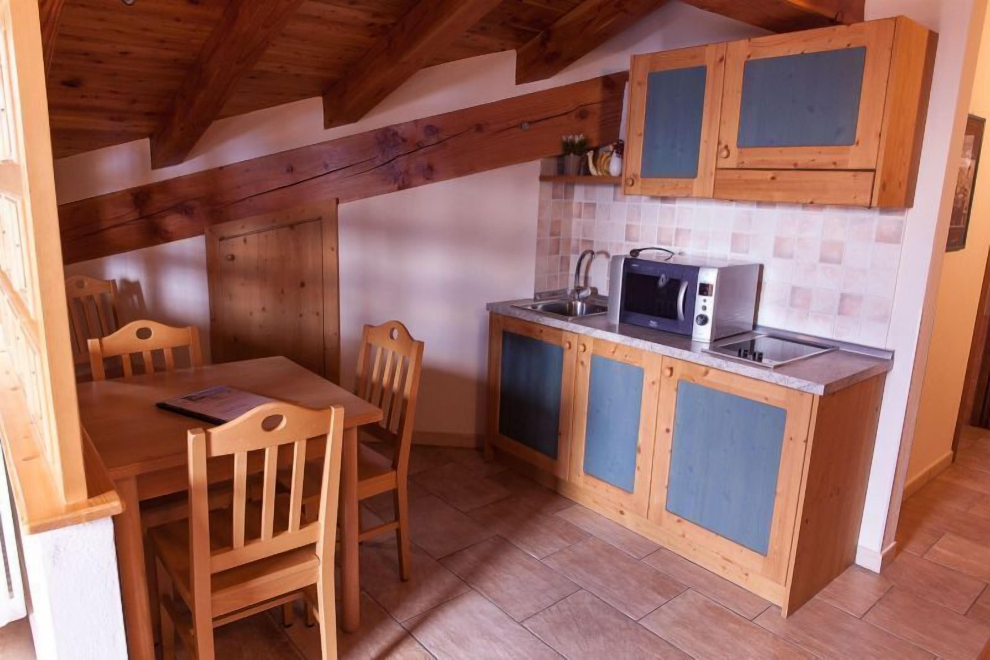 A compact kitchen with wooden cabinets, a microwave, and a sink.
