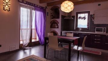 Un comedor con mesa y sillas, una cocina con microondas, y un ventanal con vistas a montañas.
