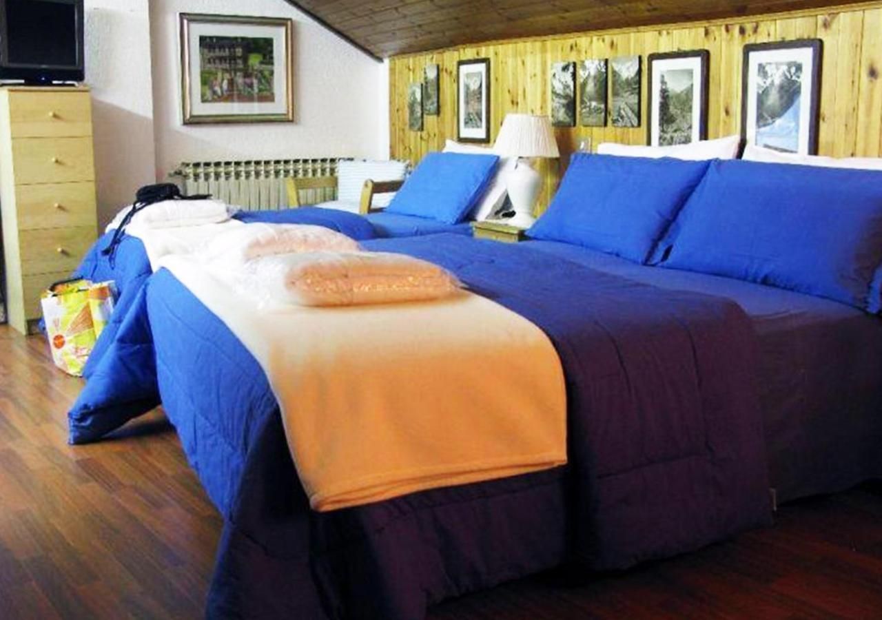 A room with a bed, a wooden dresser, a lamp, and framed pictures on the wall.