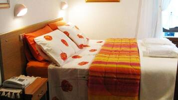 A hotel room with a bed, a nightstand, and a wall-mounted lamp.
