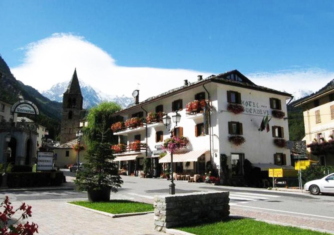 Ein Hotel mit weißer Fassade, mehreren Blumenbalkonen und einem Berg im Hintergrund.