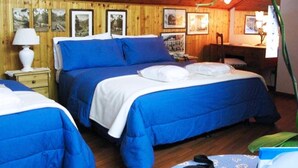 A room with two beds, wooden walls, framed pictures, a desk, and a lamp. - Hotel Bucaneve (Pre-Saint-Didier)