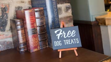 Un tavolo di legno con un cartello che offre dolcetti gratuiti per cani, circondato da libri d'epoca.