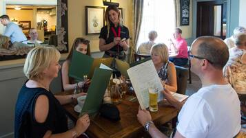 A group of people seated at a wooden table in a restaurant, reading menus.