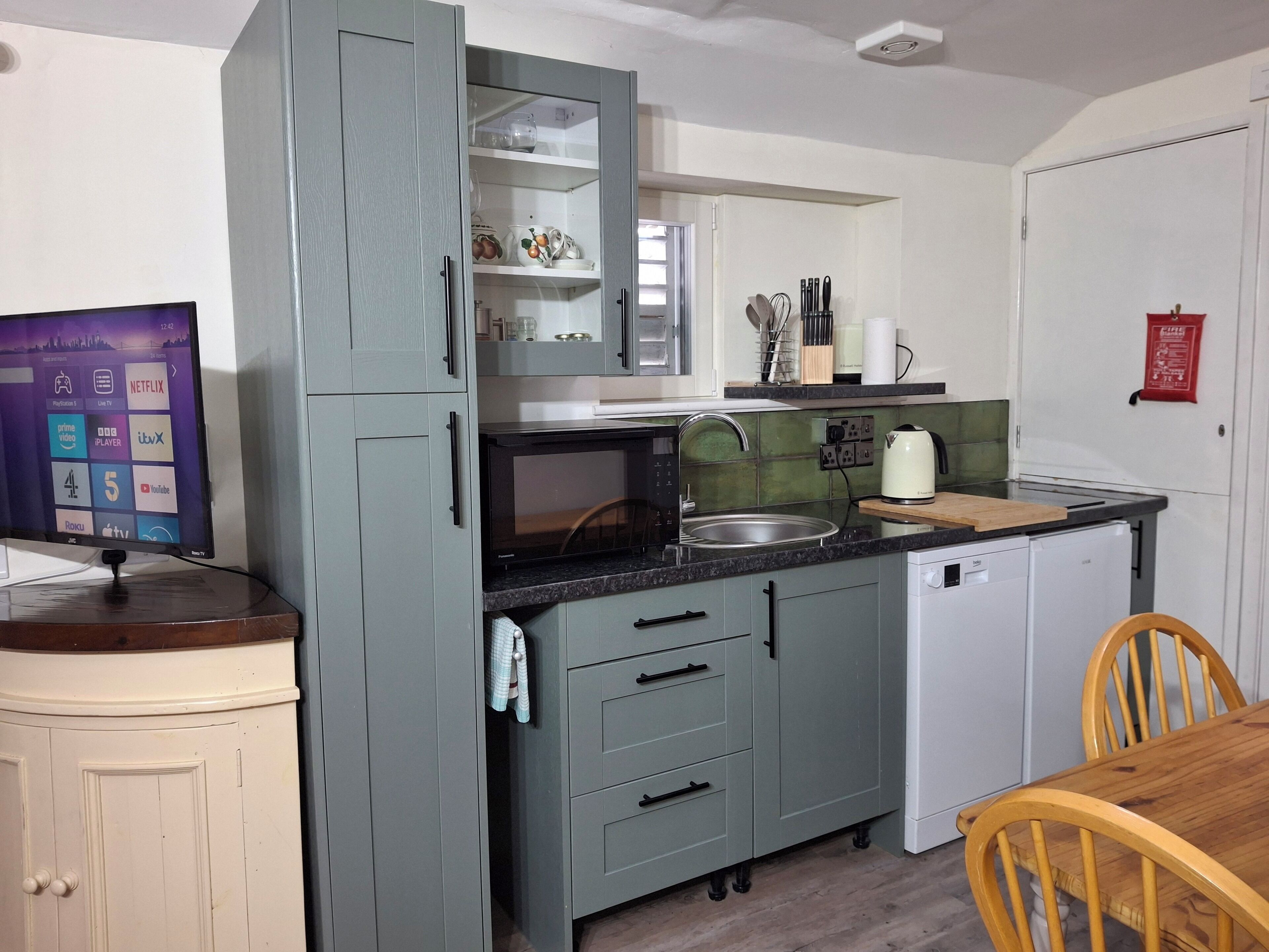 A compact kitchen with grey cabinets, a built-in microwave, a sink, and a small refrigerator.
