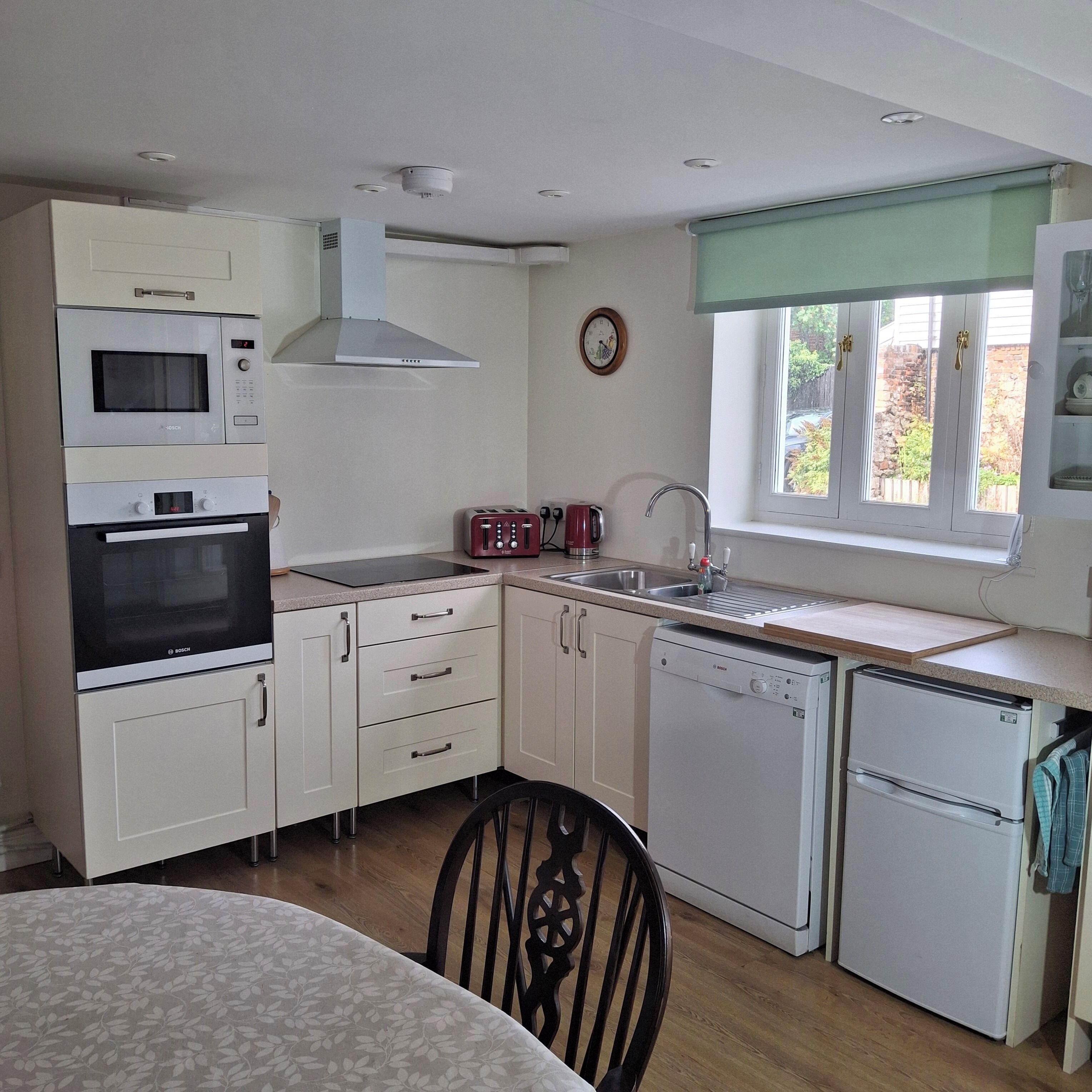 A compact kitchen with a microwave, toaster, sink, and dishwasher.