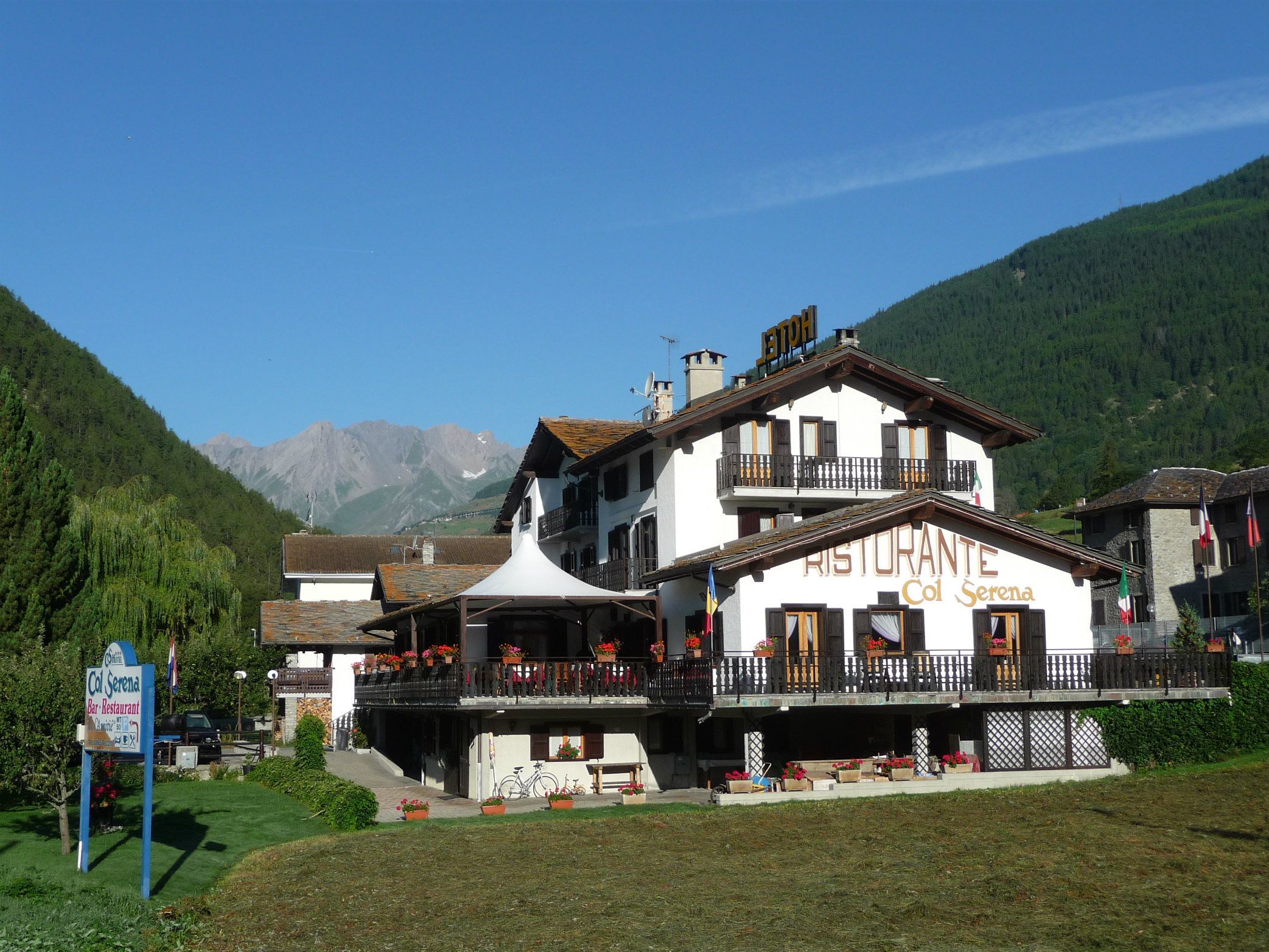 Un restaurant à deux étages, doté de balcons et entouré de montagnes et de verdure.