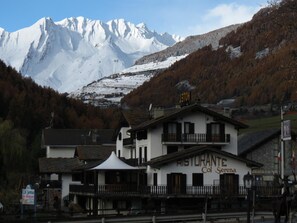 A two-story building with a sign reading "Ristorante Col Serena." It features a balcony with a railing and a mountain backdrop. - Hotel Col Serena (Etroubles)