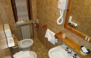 Un baño con dos inodoros, un lavabo, un espejo y un perchero para toallas.
