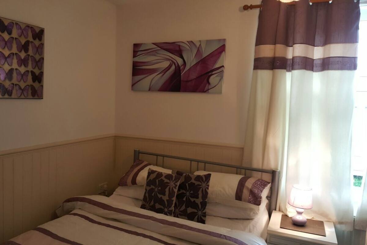 A bedroom with a bed, a nightstand, a lamp, and two wall art pieces.