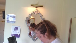 A room with a laptop on a glass table, a mirror, and a sign indicating a top-rated coffee. - Lynebank House Hotel Bed & Breakfast (Carlisle)