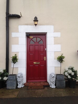 A red door with a white-framed entrance, flanked by two potted plants. - Lynebank House Hotel Bed & Breakfast (Carlisle)
