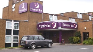 A Premier Inn hotel with a brick facade, multiple signs, and a parked car. - Premier Inn Carlisle M6 Jct44 (Carlisle)