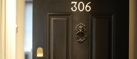 A black door with the number 306, a brass knocker, and a keyhole.