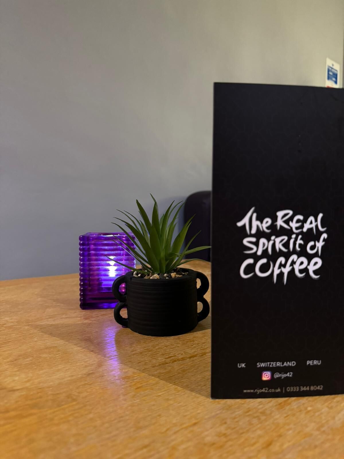 A black book titled "The Real Spirit of Coffee" on a wooden table.