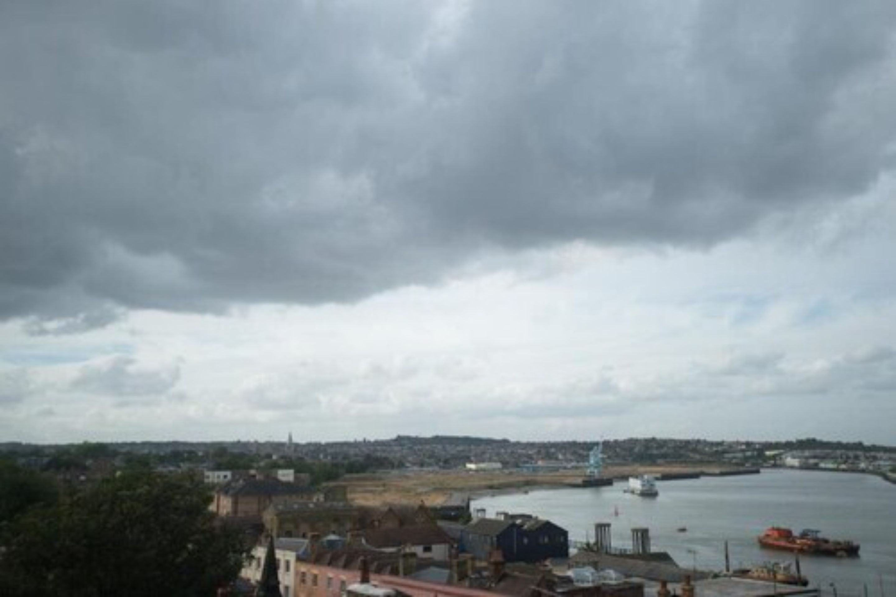 A coastal town with a harbor, buildings, and a cloudy sky.
