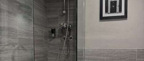 Un baño moderno con ducha de vidrio, inodoro y un cuadro en la pared.