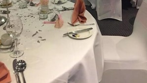 Une salle de banquet avec des tables rondes, des nappes blanches et des chaises recouvertes de housses transparentes.