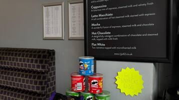 A menu board with coffee options and a display of snacks and chocolates.