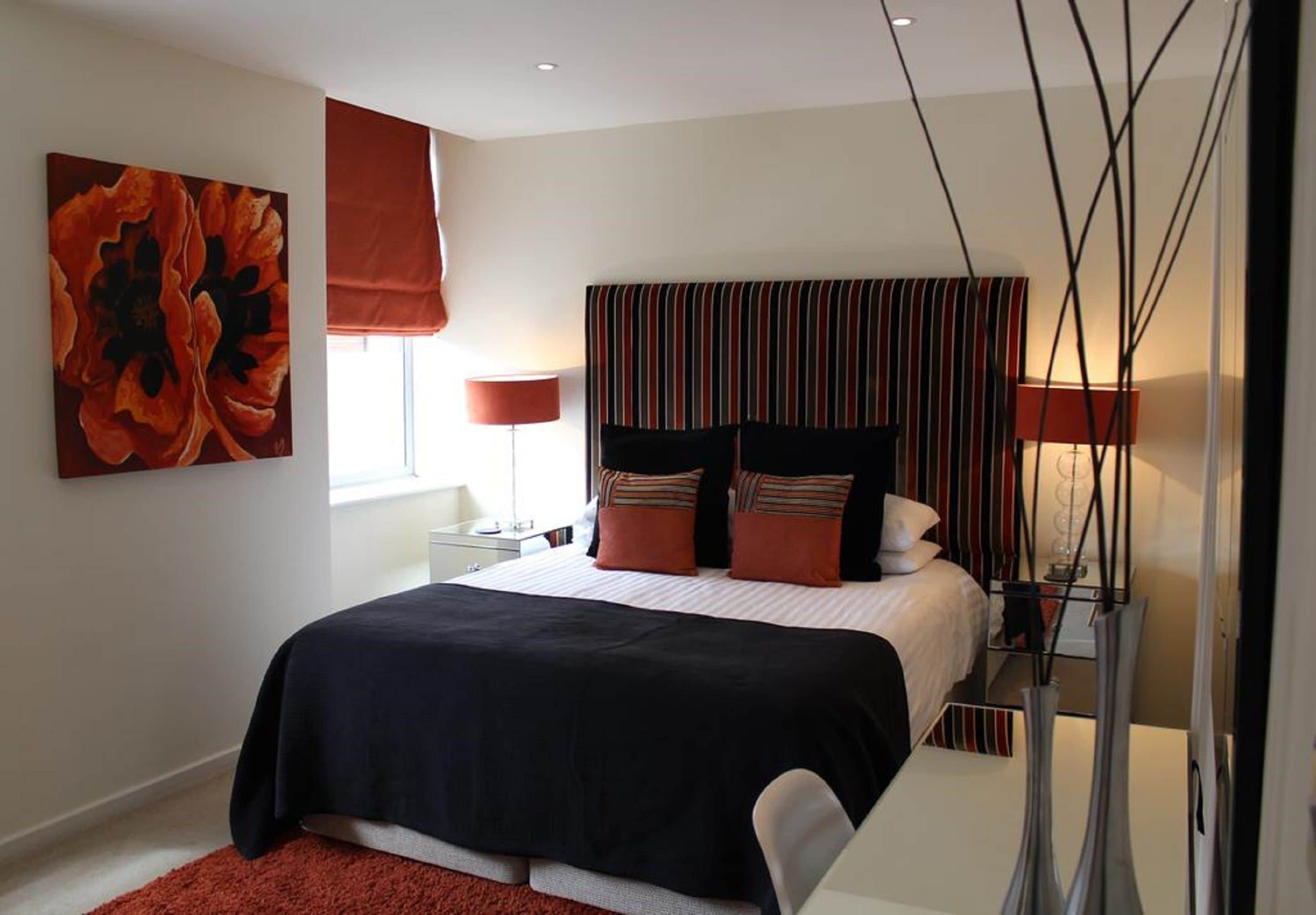 Ein modernes Schlafzimmer mit einem großen Bett, einem gestreiften Kopfteil und einem roten abstrakten Gemälde.