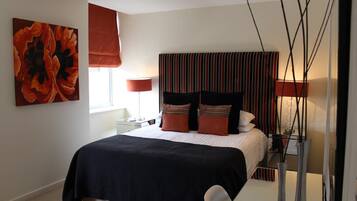 A modern bedroom with a large bed, striped headboard, and a red abstract painting.