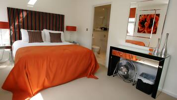 A hotel room with a large bed, a desk with a mirror, and a bathroom visible through an open door.