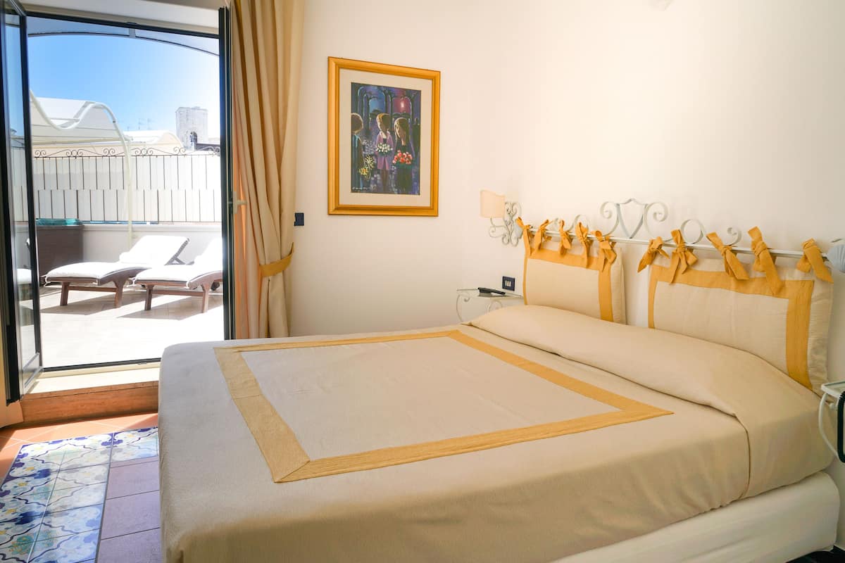Una habitación de hotel con una cama, un balcón con una silla y un cuadro en la pared.