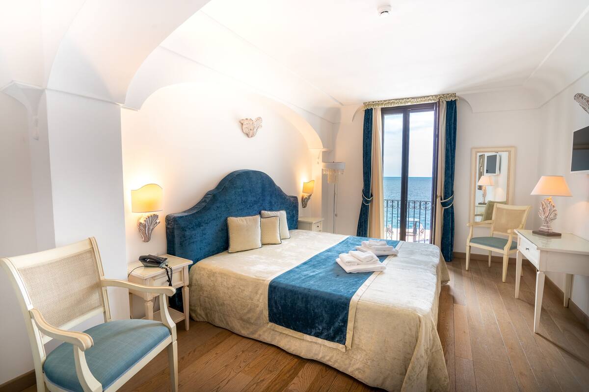 Habitación de hotel con una cama grande, un escritorio, una silla y vista al mar.