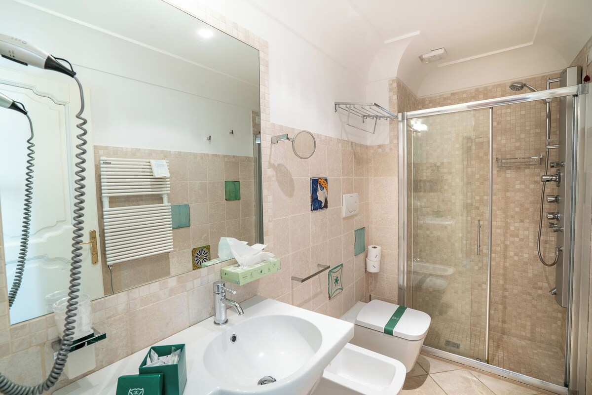 A bathroom with a glass-enclosed shower, a sink, a toilet, and a telephone.