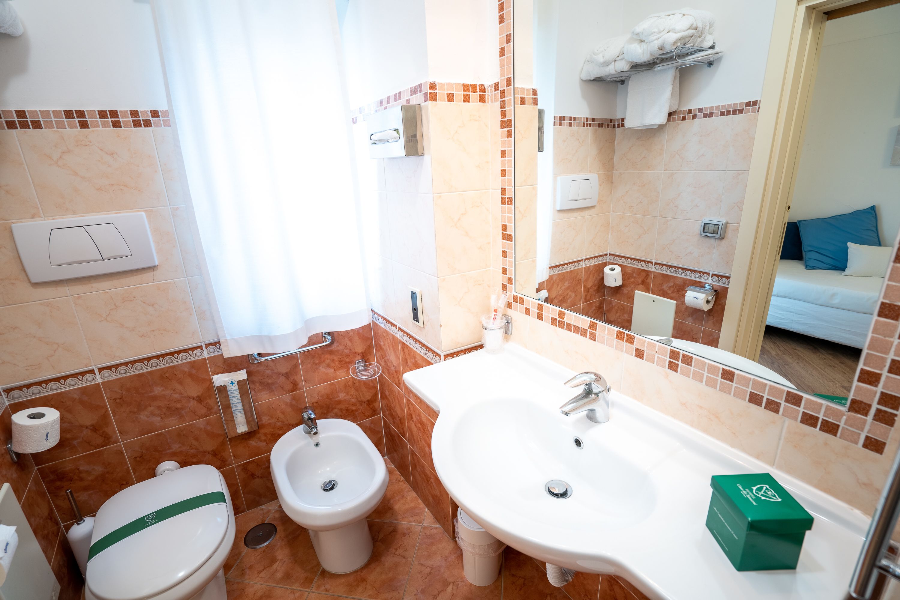 Un baño con inodoro, bidé, lavamanos y espejo.