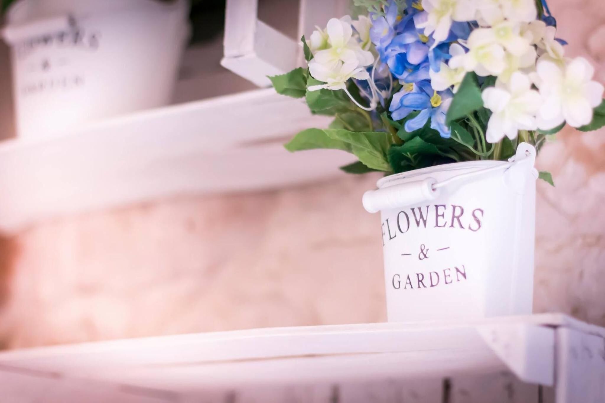 Een witte container met de tekst 'FLOWERS & GARDEN', met een boeket bloemen.