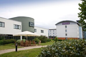 A hotel with outdoor seating, a sign for 'Inn on the Park,' and a 'Premier Inn' building. - Premier Inn London Enfield (Enfield)