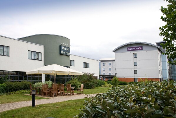 A hotel with outdoor seating, a sign for 'Inn on the Park,' and a 'Premier Inn' building. - Premier Inn London Enfield (Enfield)