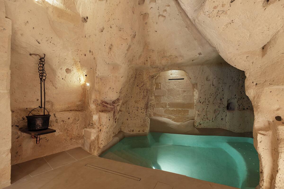 An indoor swimming pool with stone walls and a hanging bucket.
