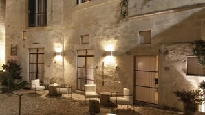 A stone-walled courtyard with seating areas and a staircase. - Corte San Pietro (Matera)