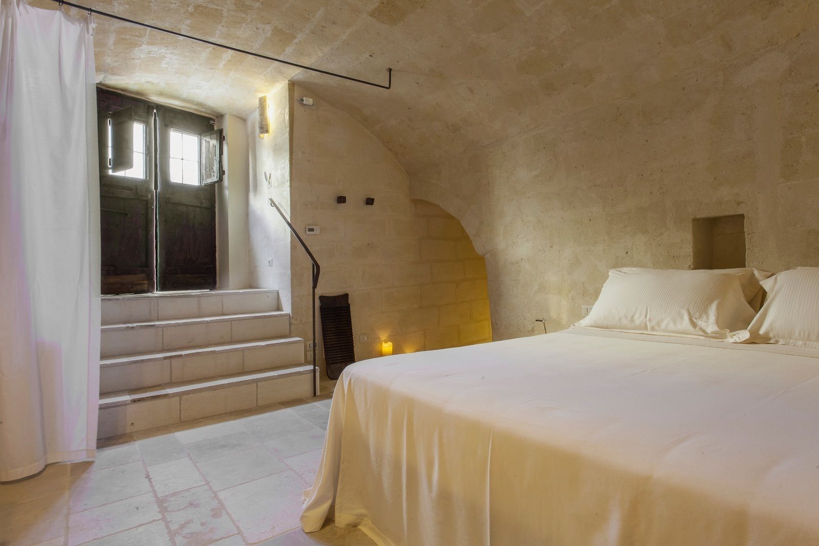 A bedroom with a bed, a window, and a staircase leading to an upper level.