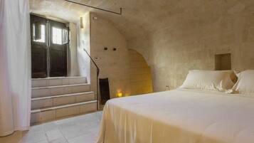 A bedroom with a bed, a window, and a staircase leading to an upper level.