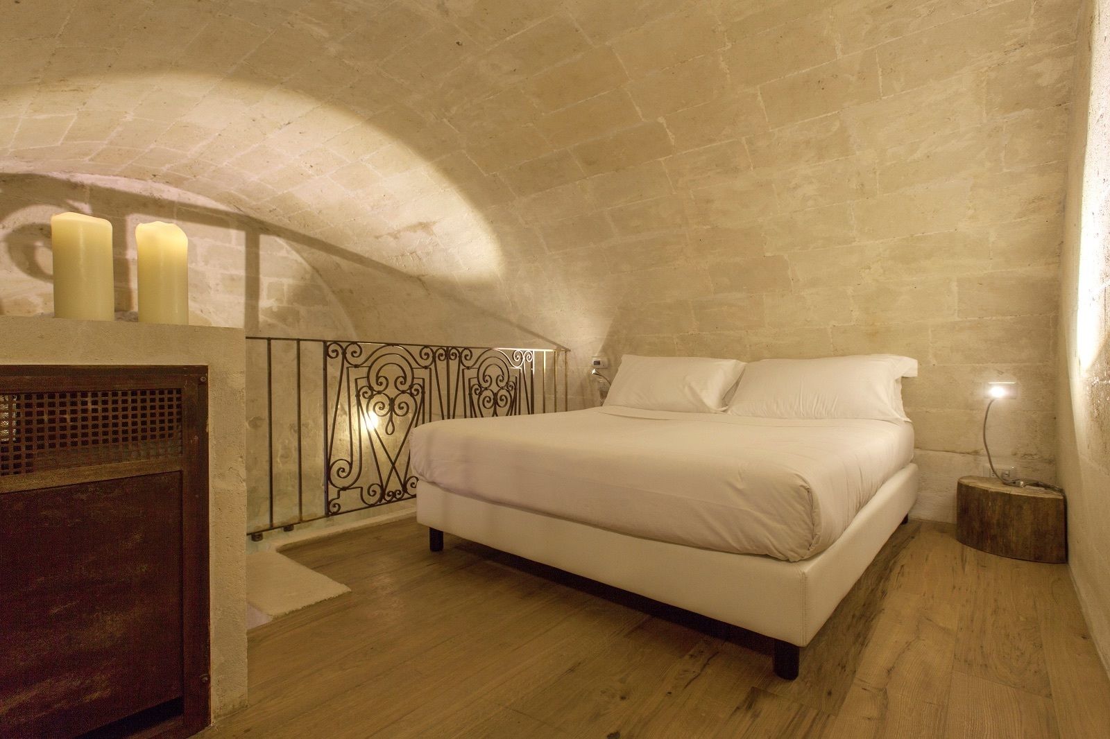 A bedroom with a bed, a nightstand, a dresser, and three candles.