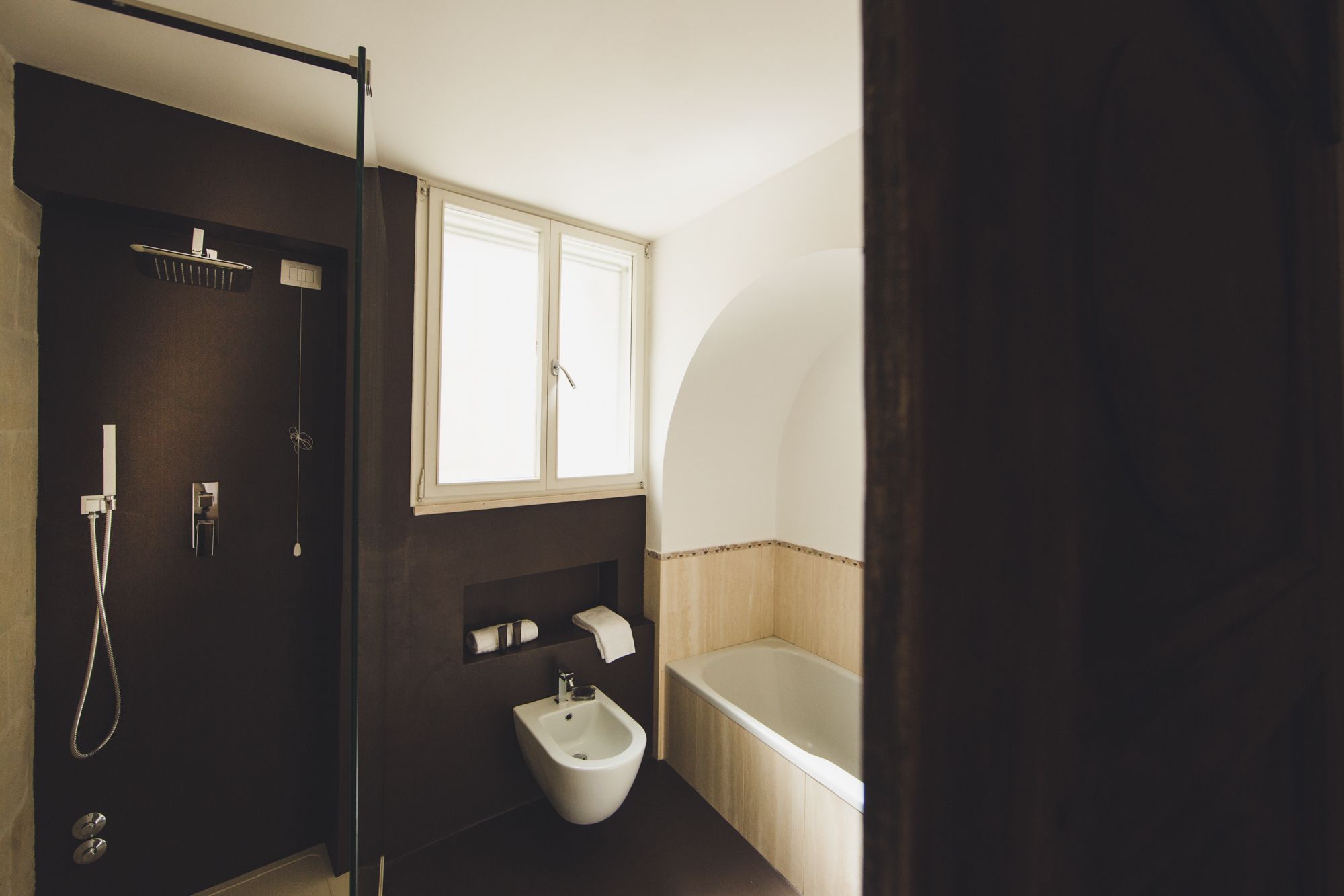 A bathroom with a bidet, a bathtub, and a window.