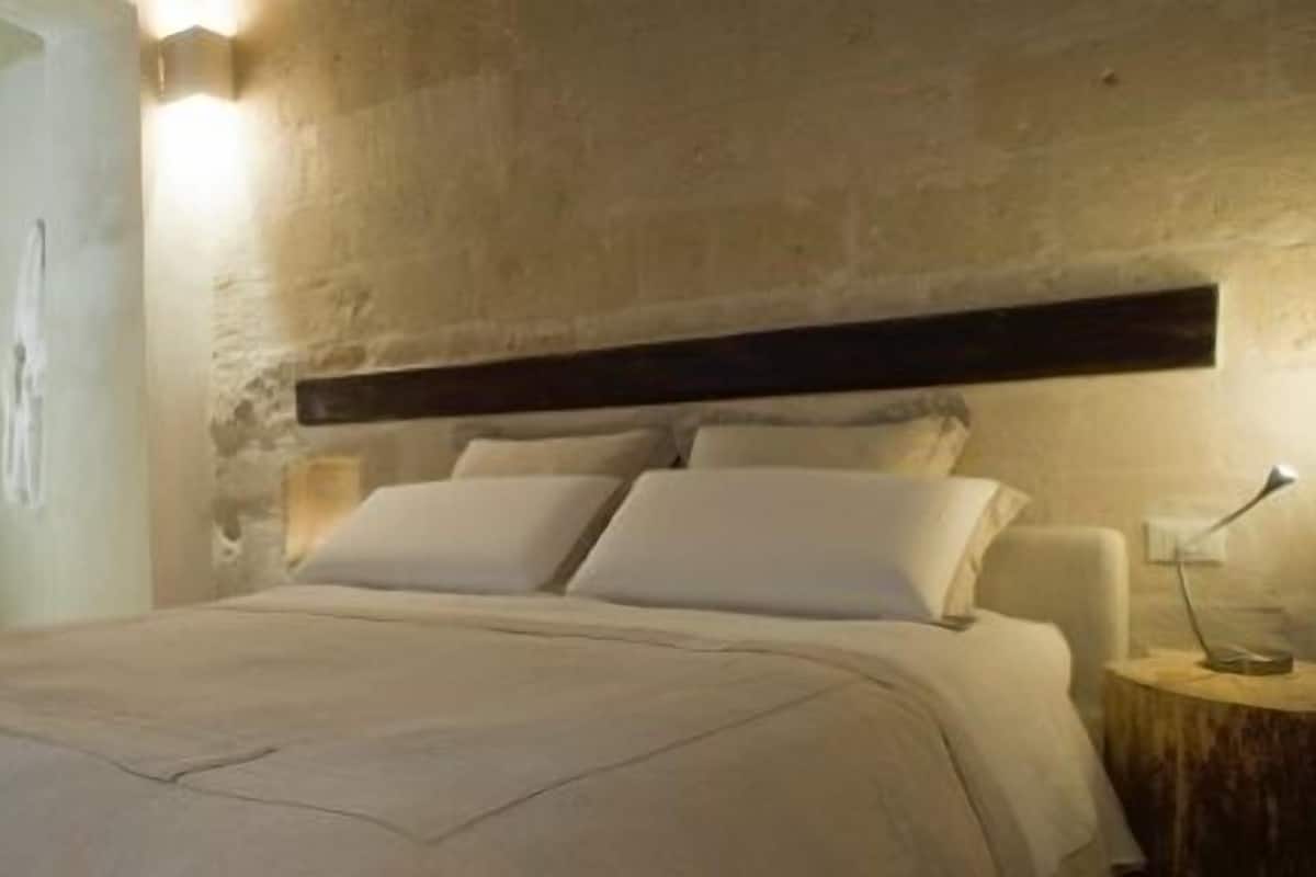 A bedroom with a bed, a nightstand, and a wall-mounted light fixture.
