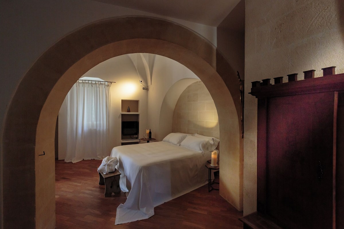 A bedroom with a bed, a nightstand, a TV, and a wardrobe.