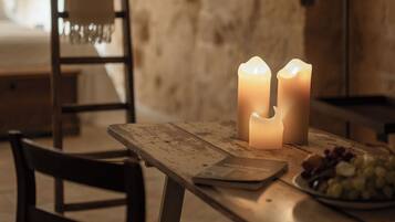 Una mesa de madera rústica con velas, una silla y un plato de uvas.