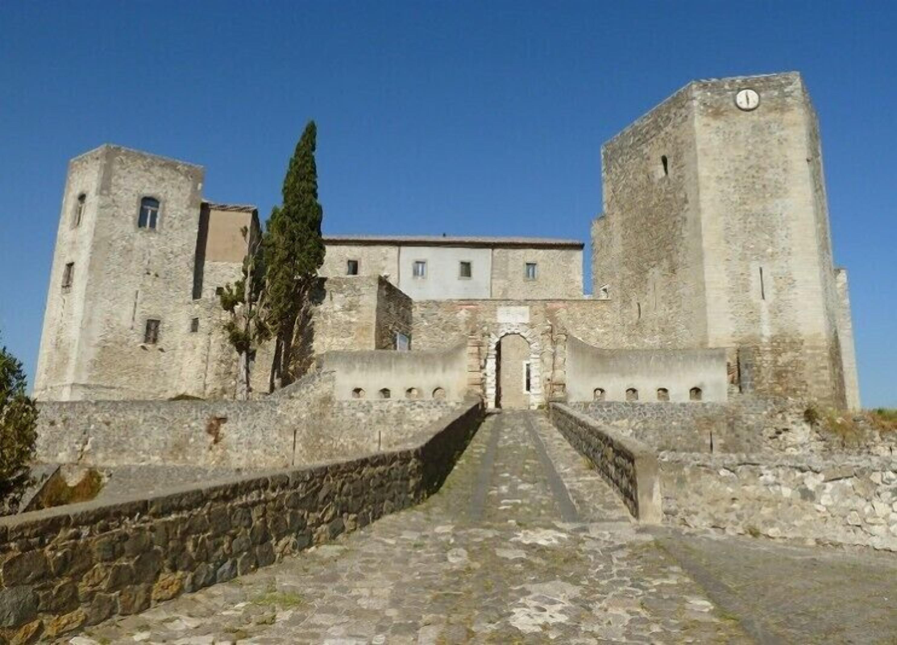 Un castillo de piedra histórico con una entrada central, dos torres y una muralla que lo rodea.