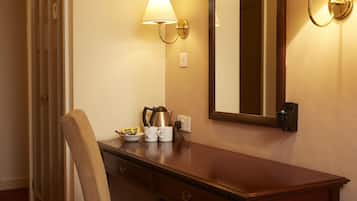 A hotel room with a wooden dresser, a chair, a mirror, and a lamp.
