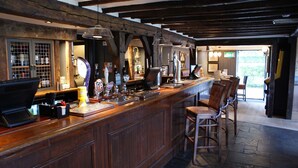 A bar area with wooden beams, a counter with taps, and bar stools. - Two Brewers by Chef and Brewer Collection (Kings Langley)